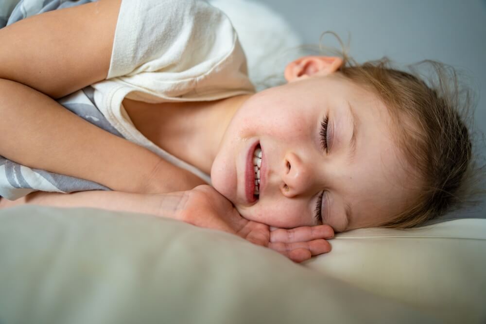 A little girl peacefully sleeping on a pillow, highlighting the importance of addressing untreated bruxism.