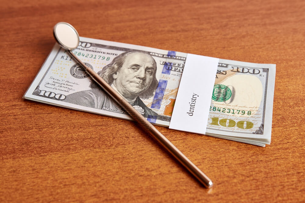 A spoon rests beside a hundred dollar bill on a wooden table, symbolizing cost-effective choices for families.