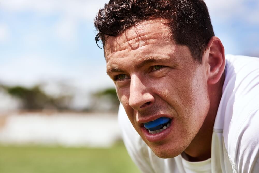 A man wearing a blue sports guard in his mouth, showcasing dental protection during athletic activities.