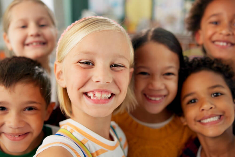 A cheerful group of children smiling together for the camera, showcasing their bright personalities and joy.